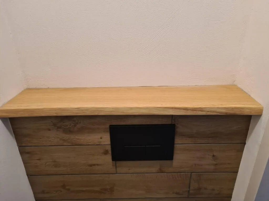 Eiken afdekplank op een toiletombouw met houten voorzijde