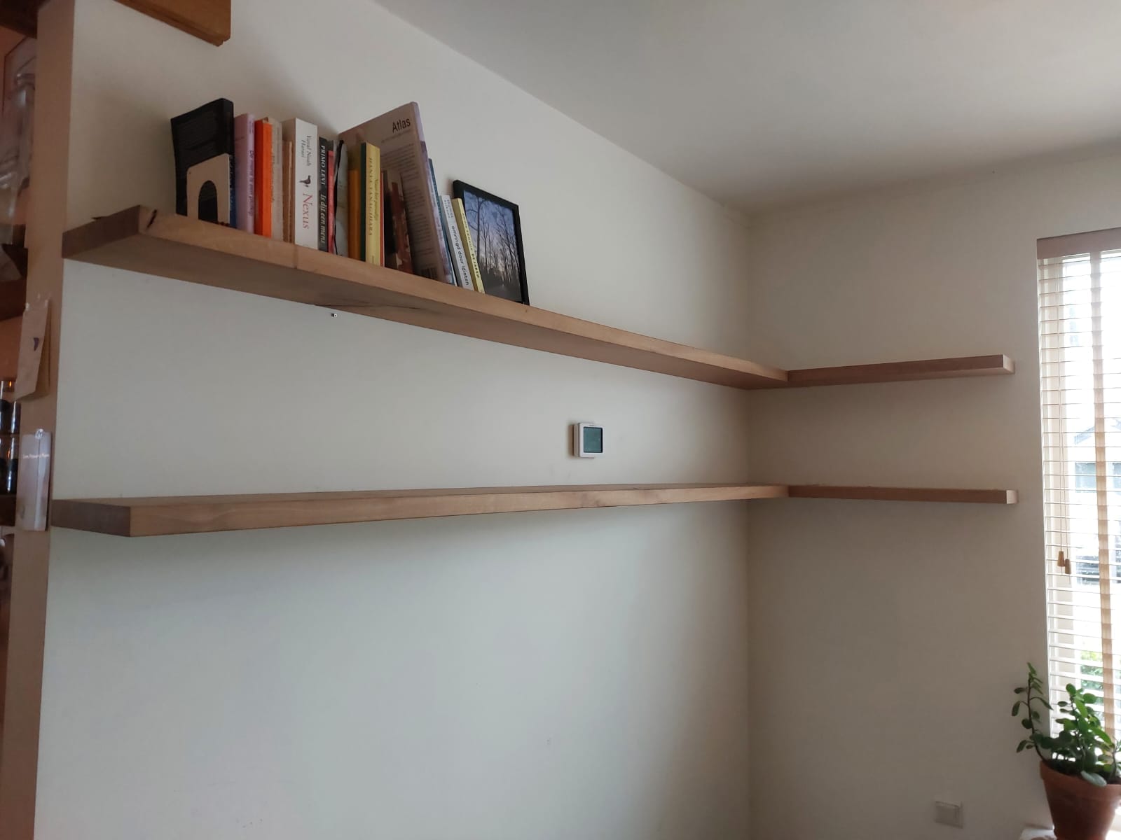 Twee eiken hoekplanken langs witte muren met boeken op de bovenste plank