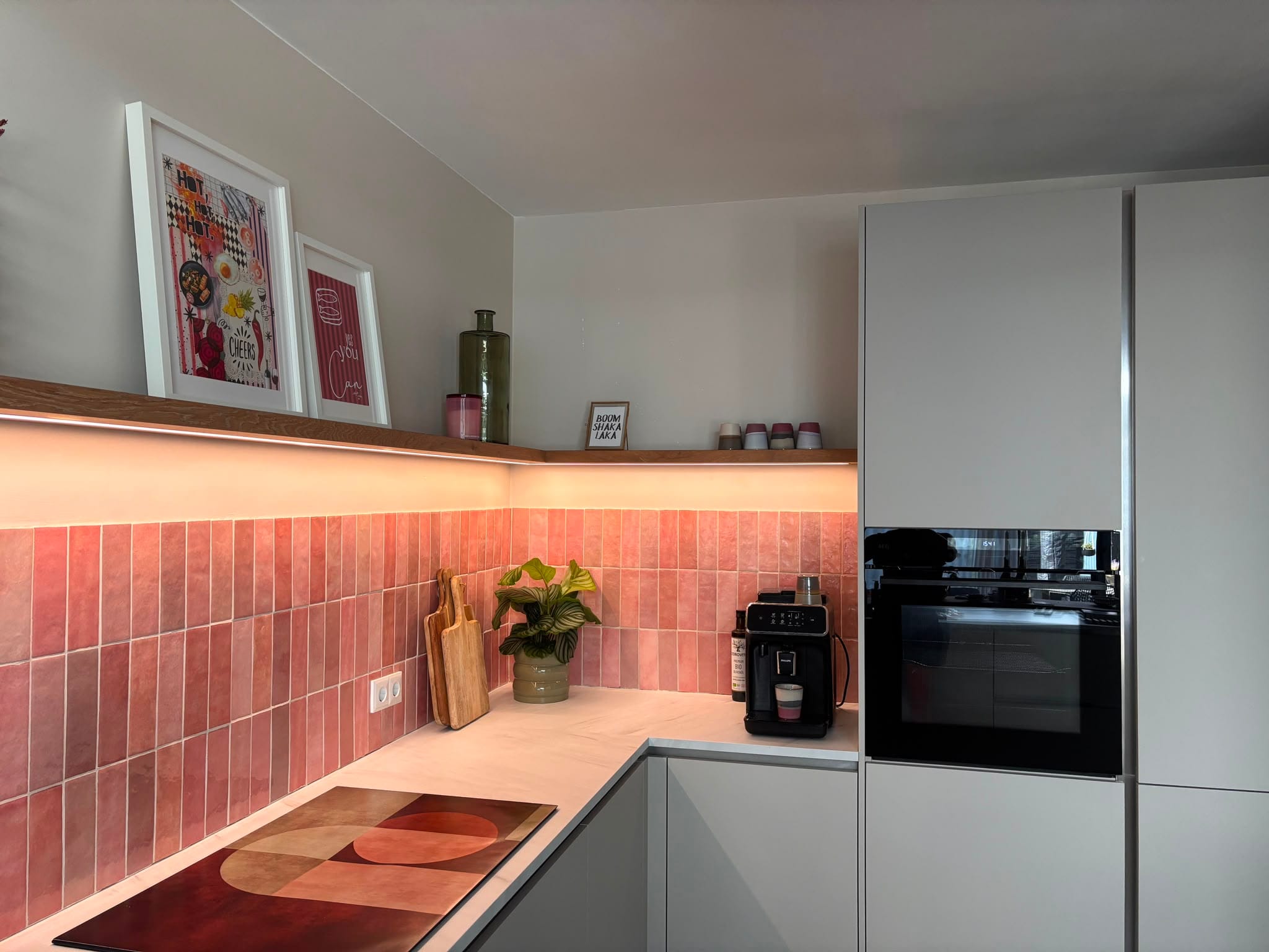 Eiken hoekplank met LED-strip boven een keuken met roze wandtegels