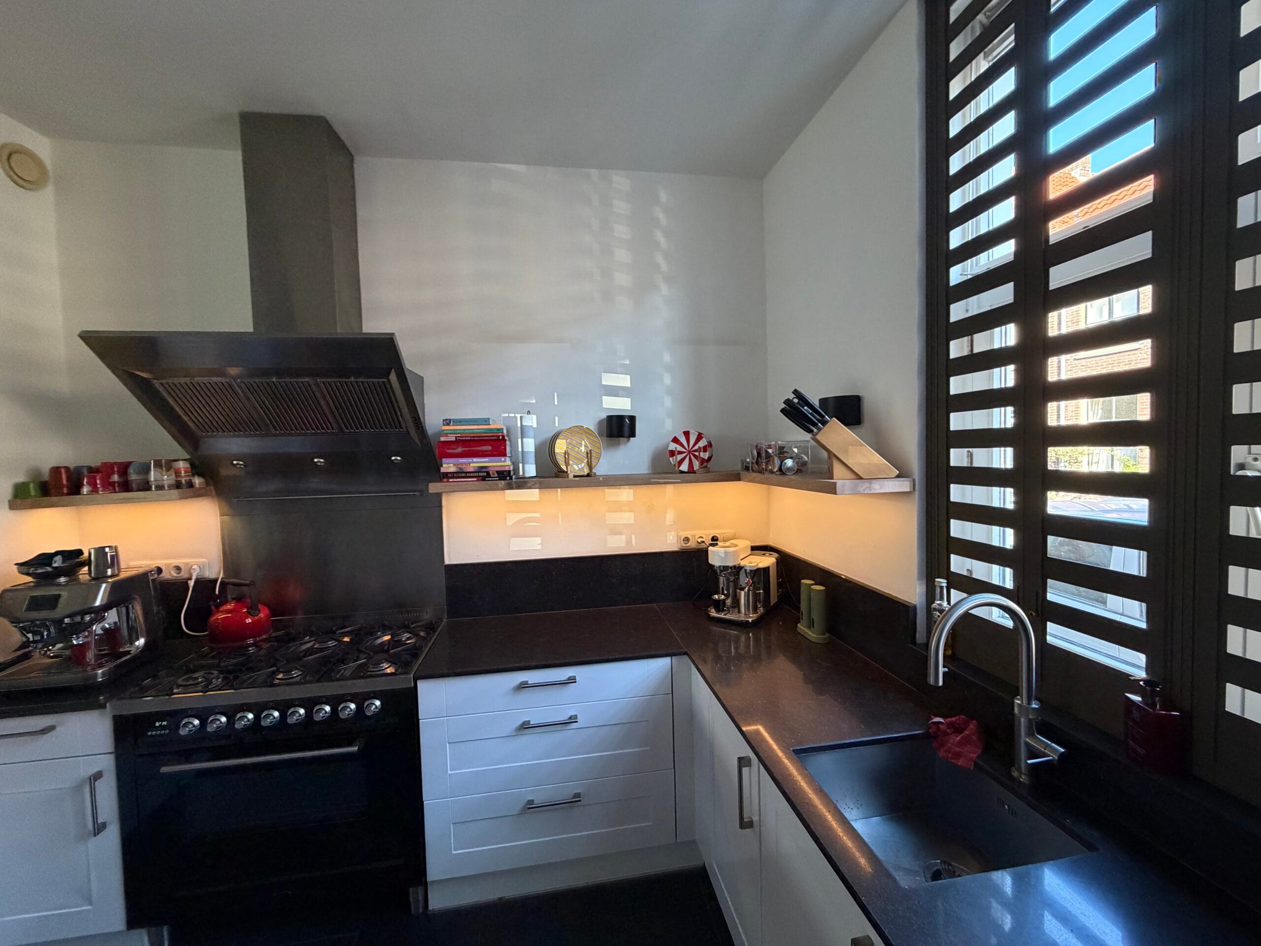 L-vormige eiken plank met LED-verlichting boven een donkere keuken